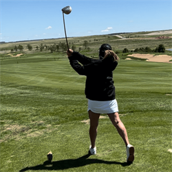 A girl in the middle of a golf swing